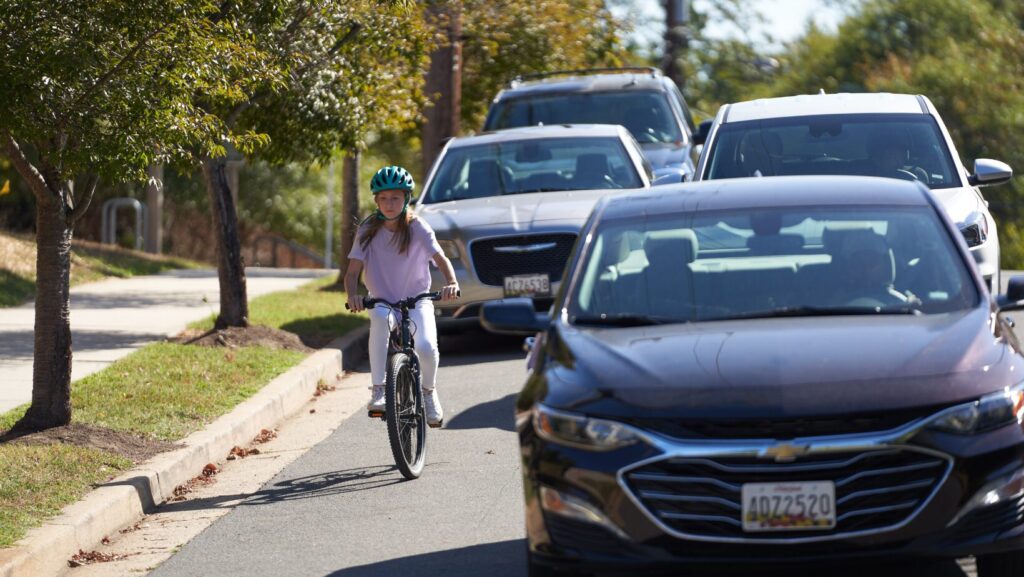 girl riding bike near cars