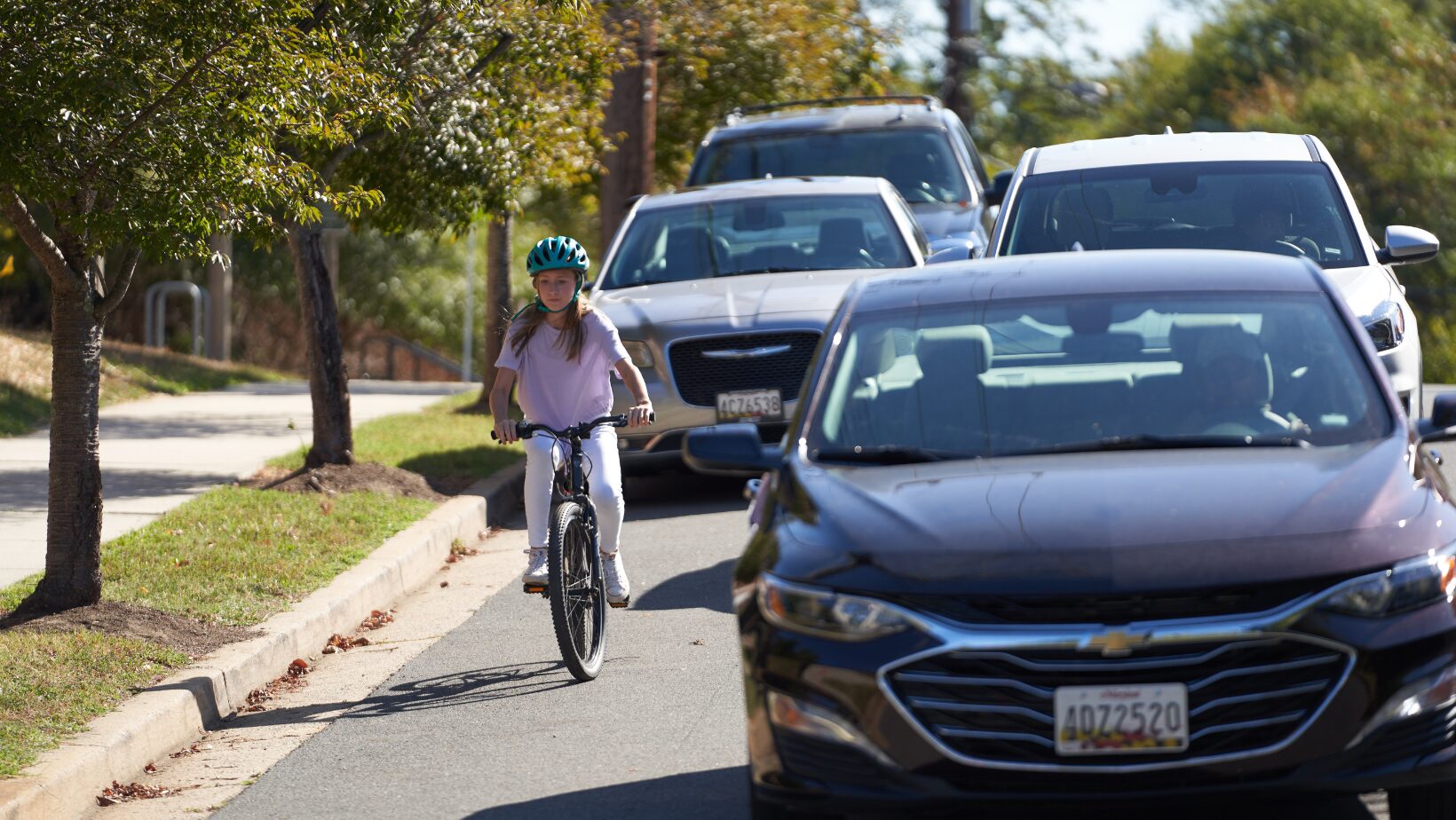 girl riding bike near cars