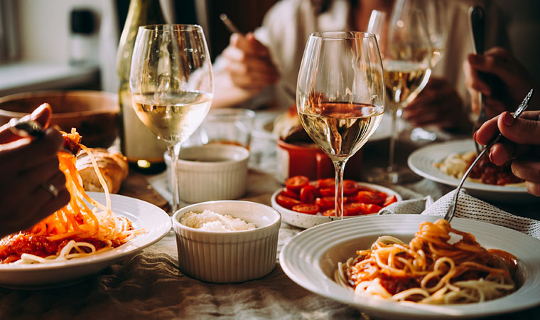 group of friends sitting at table eating spaghetti