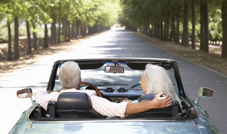 elder couple driving sports car