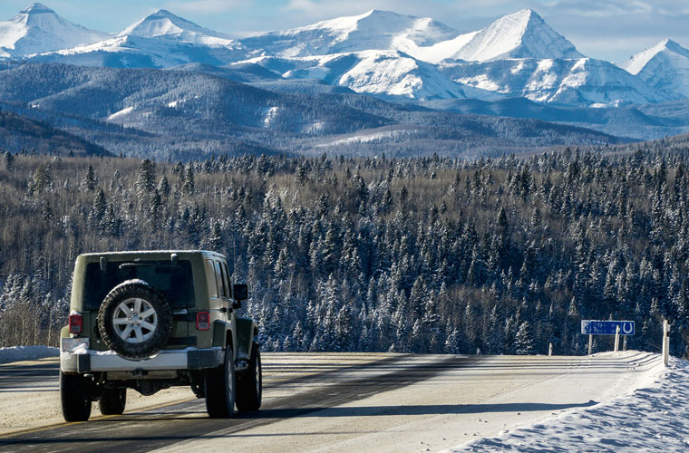 Jeep driving toward snow covered mountains in the distance