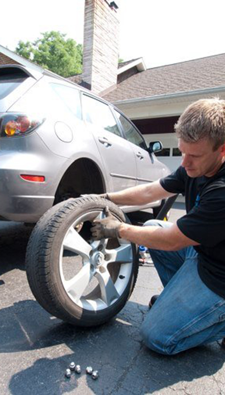 Man removing lug nut from tire on car