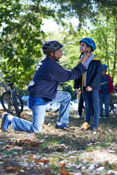 dad with child securing bicycle helmet