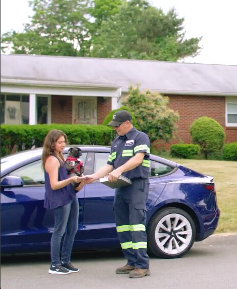 woman with dog and technician outside of an electric vehicle