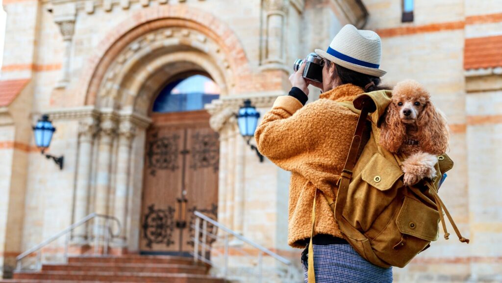 woman outside an exotic villa with dog in backpack
